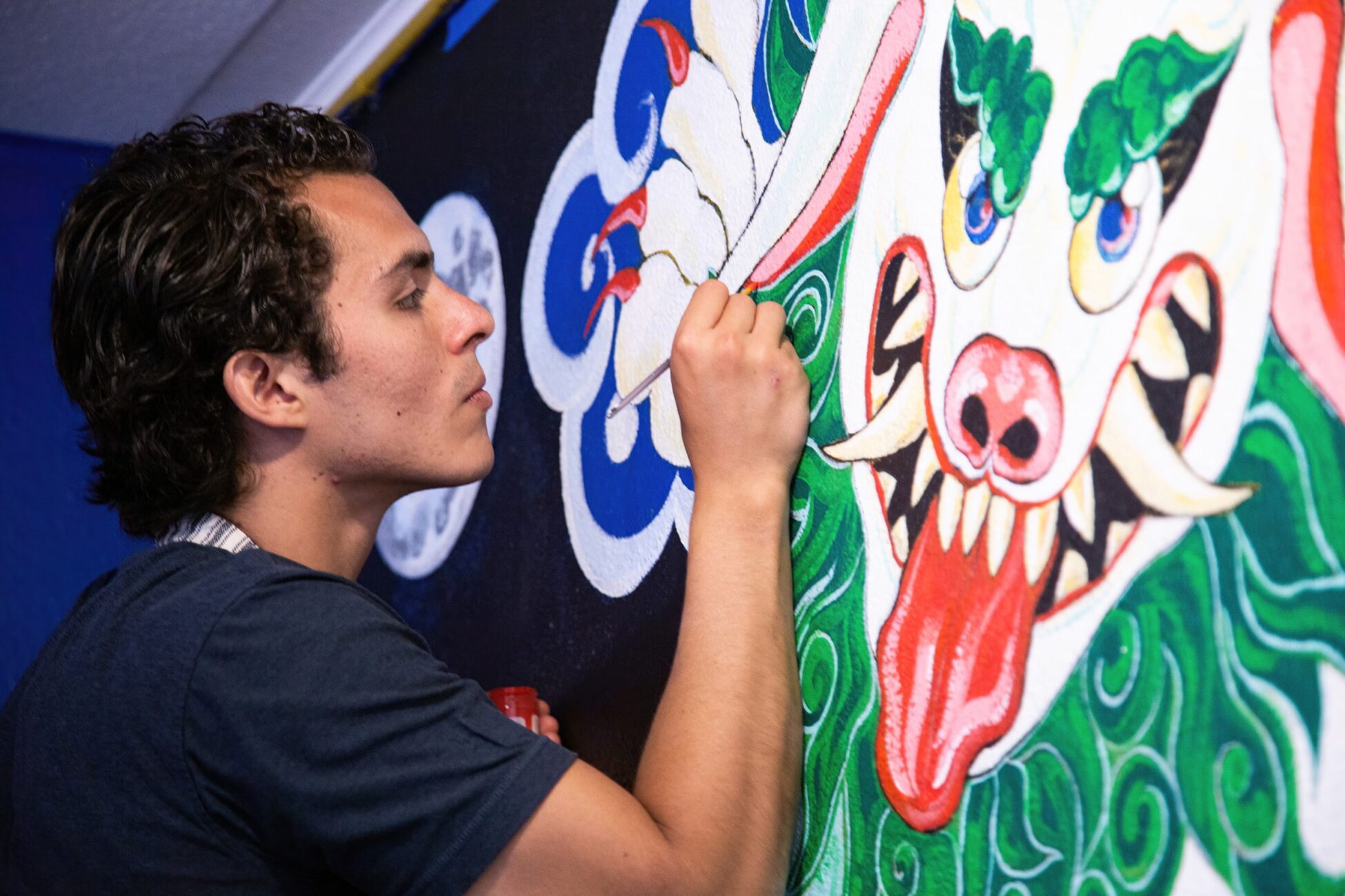 Juan Pablo Fernández Garcí painting a mural in naropa's Little Lama Cafe