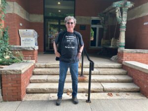 Naropa graduate Joe Richey standing on the steps of the Allen Ginsberg Library