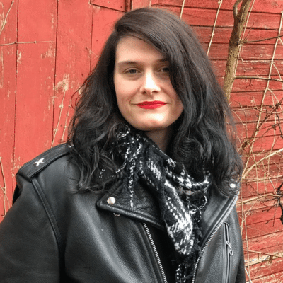 Katie Jean Shinkel in a black leather jacket, in front of brick