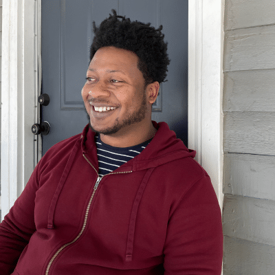 Steven Dunn in a red hoodie on the porch, smiling