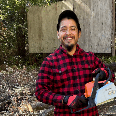 Angel Dominguez in a red and black flannel shirt with hat and smile