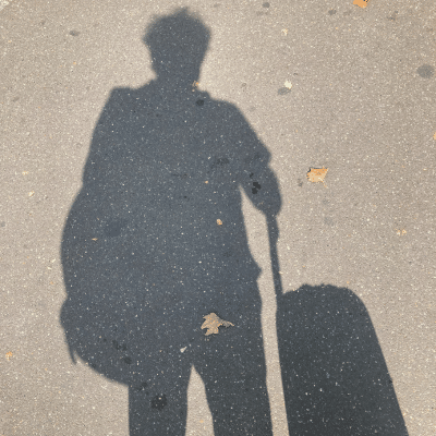 anselm berrigan shadow on pavement with suitcase.