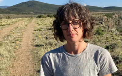 poet kelly krumrie on a dirt road, mountains behind. from author site