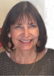 Image of Valerie, smiling with meditation cushions in the background